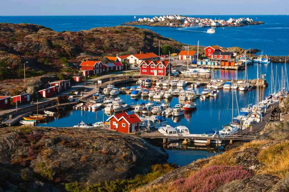 Port de pêche de la côte du Bohuslän, avec ses chalets en bois rouges et ses dizaines de bateaux dans une baie calme, par une journée ensoleillée d'été.