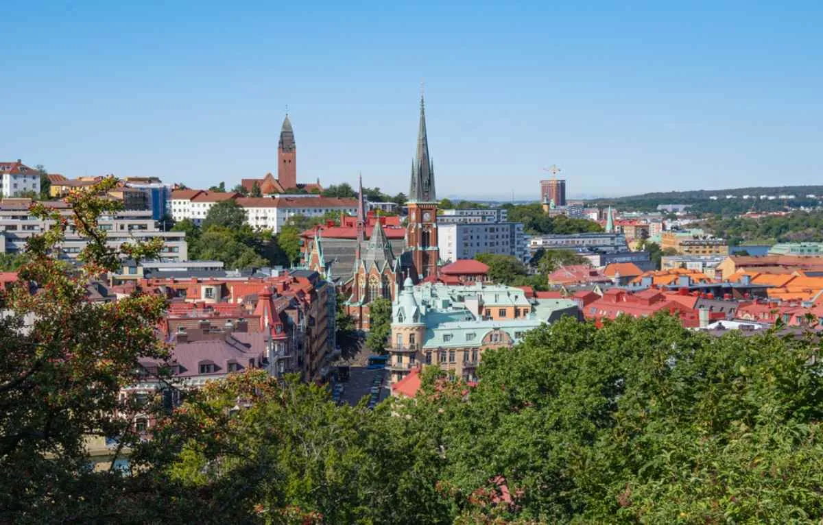 Panorama de Göteborg avec ses toits colorés et ses clochers, vu depuis une colline sous un ciel bleu limpide.