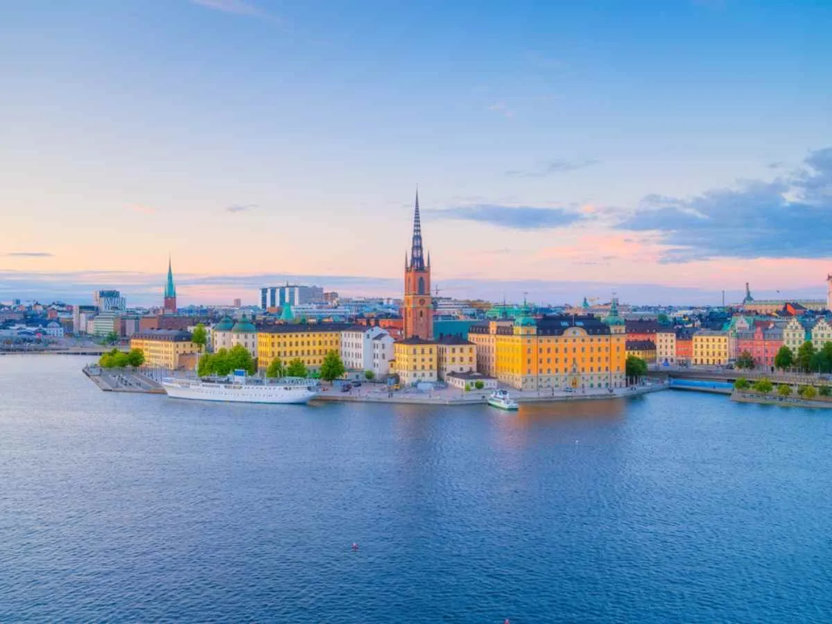 Gamla Stan et le clocher de l'église de Riddarholmen, entourés par les eaux calmes du port sous un ciel aux teintes pastel.