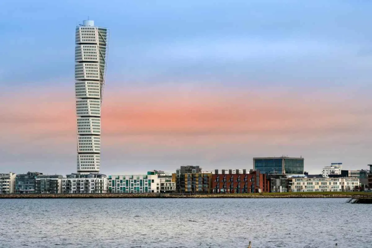 La ligne d'horizon du front de mer de Malmö, avec le gratte-ciel torsadé « Turning Torso » qui s'élève au-dessus d'immeubles d'habitation modernes au crépuscule.