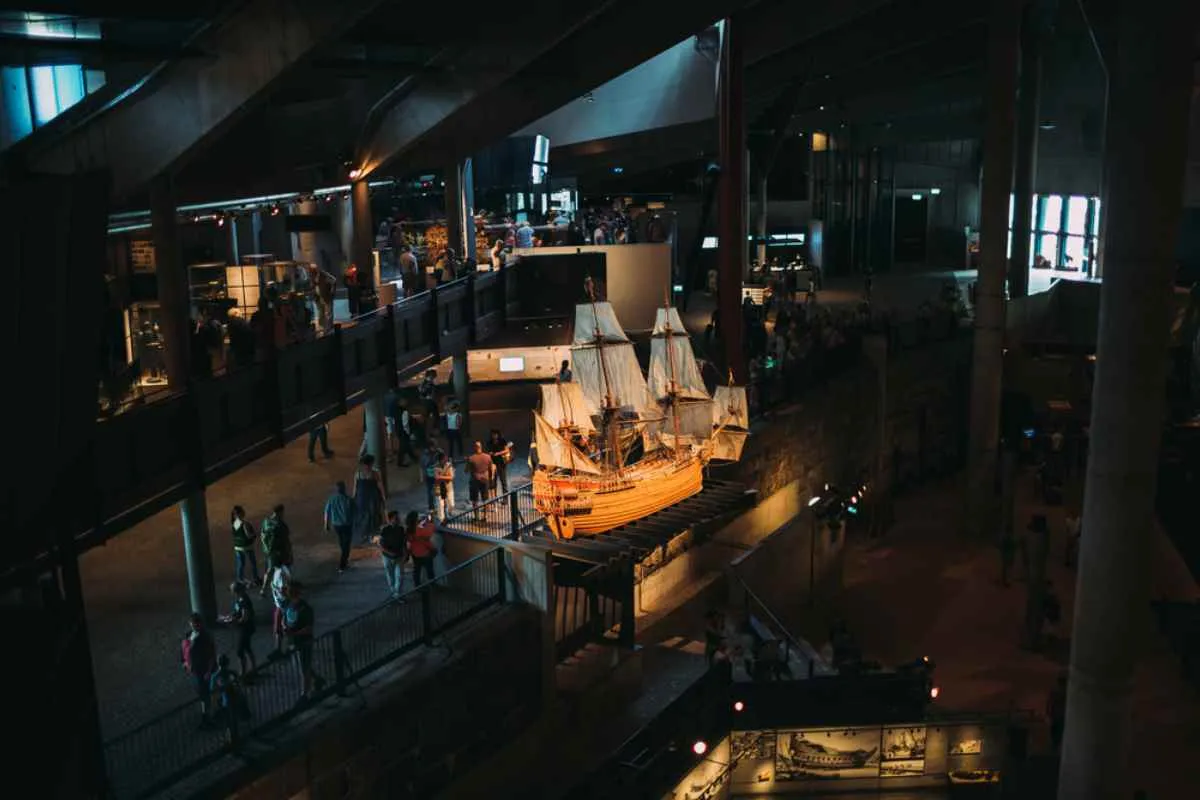 Intérieur du musée Vasa à Stockholm, où des visiteurs se promènent autour de l'imposant navire de guerre du XVIIe siècle conservé dans ce lieu.