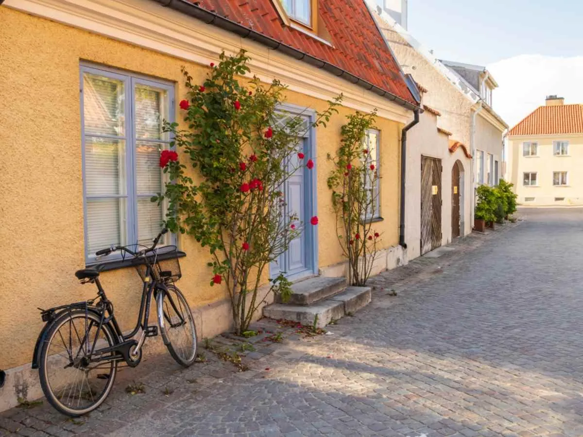 Charmante rue pavée à Visby, sur l’île de Gotland, avec ses maisons aux couleurs pastel, ses rosiers grimpants et un vélo appuyé contre le mur.