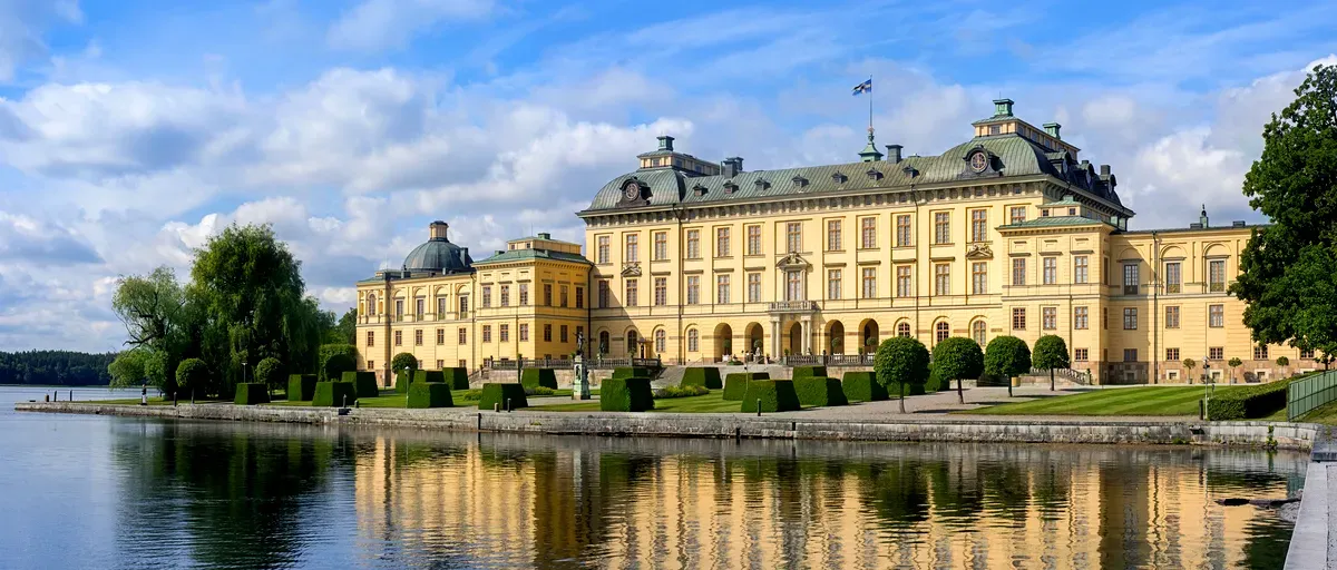 Vista panorámica del Palacio de Drottningholm en Suecia, con su majestuosa arquitectura reflejada en las tranquilas aguas.