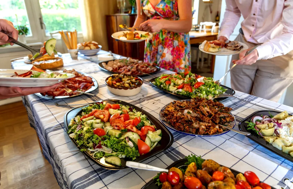 Un smorgasbord suédois haut en couleur, composé de diverses salades, viandes et autres plats servis sur une table, où les convives se servent à volonté.