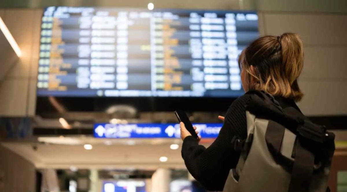 Una donna che controlla gli orari delle partenze e degli arrivi all’aeroporto