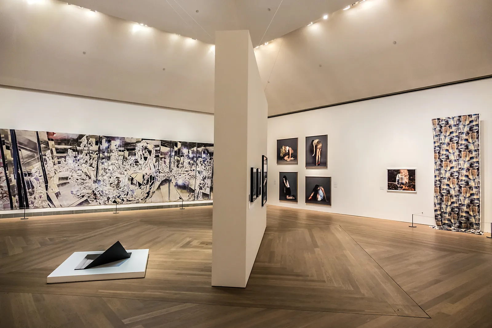 Vue intérieure d’une salle d’exposition du Moderna Museet, présentant des installations d’art contemporain et des photographies exposées sur des murs blancs minimalistes, avec un parquet et un éclairage tamisé.
