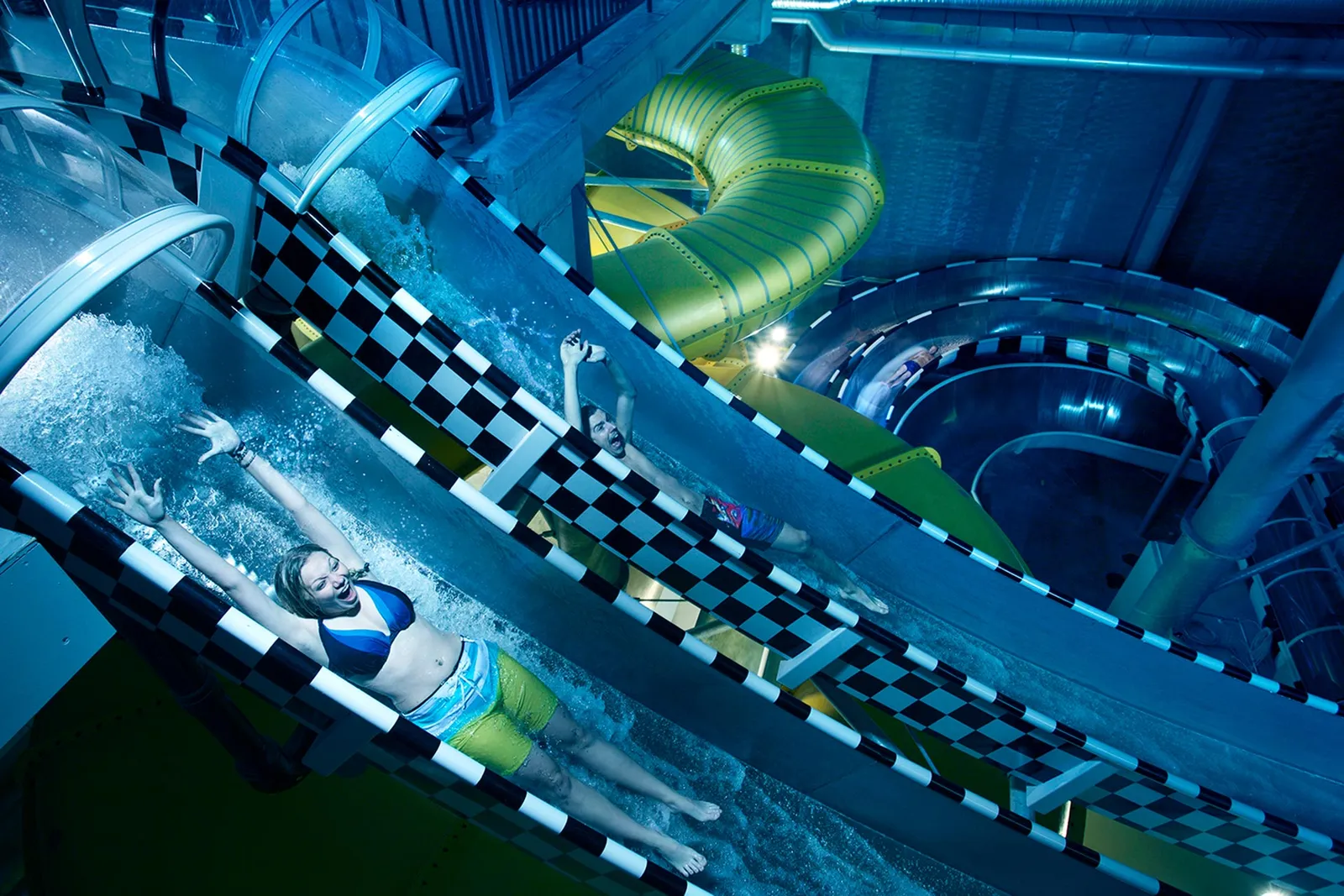 Amanti del brivido che si divertono su uno scivolo acquatico ad alta velocità al Kokpunkten Actionbad di Västerås, in Svezia, in un ambiente vivace e dinamico che esalta questa esperienza adrenalinica.