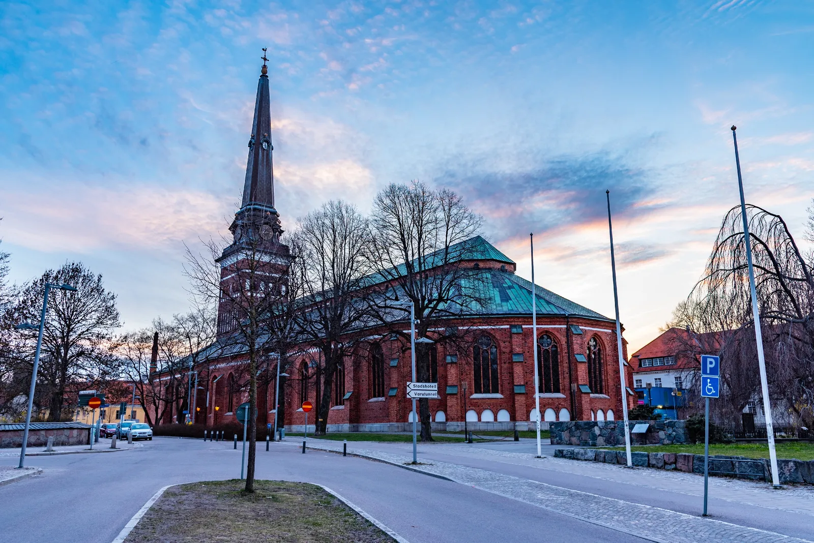 Esterno della Cattedrale di Västerås, che mette in risalto il maestoso design architettonico con guglie svettanti e dettagli intricati sullo sfondo di un cielo nuvoloso.