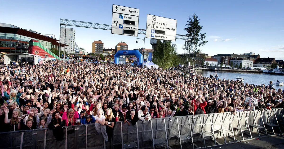 Una gran multitud entusiasmada asiste al Luleå Hamnfestival en Suecia, disfrutando de las fiestas al aire libre y de los conciertos en directo en un ambiente urbano lleno de vida.