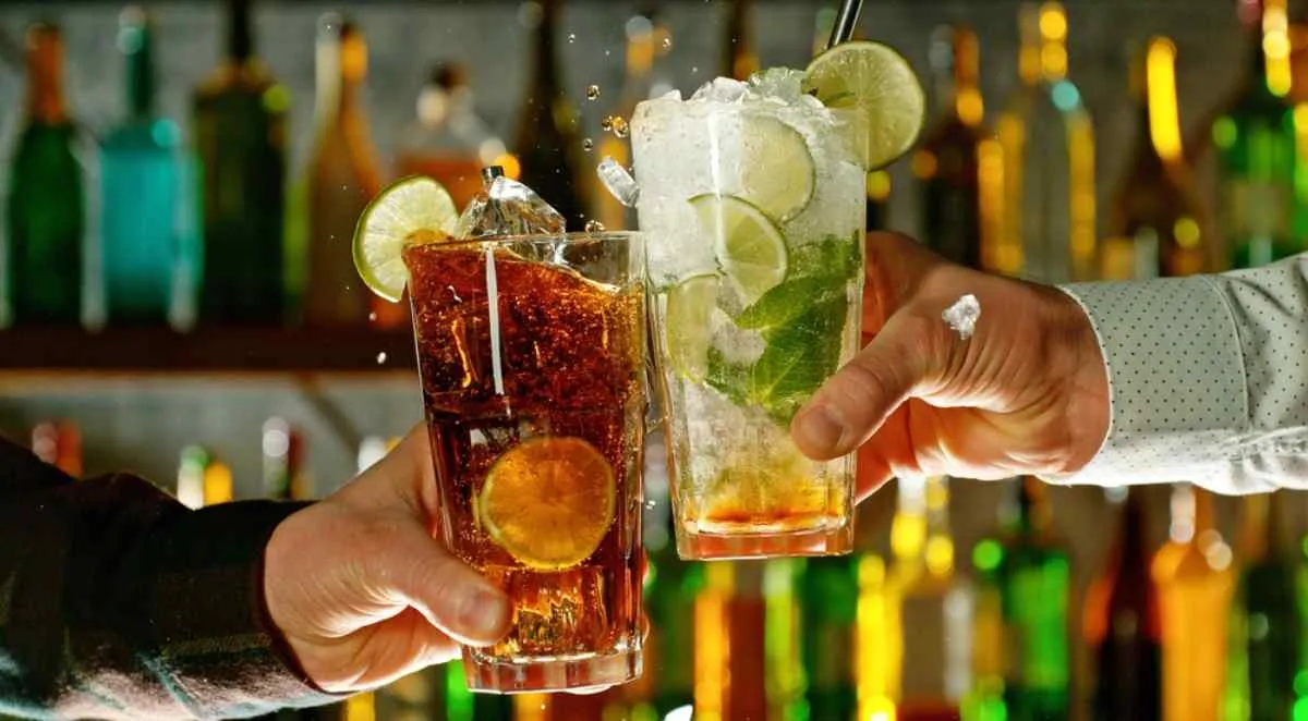 Deux mains tenant des verres à cocktail, trinquant dans un bar de Stockholm