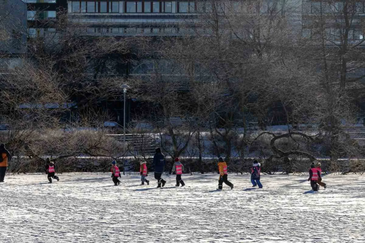 Översikt över Trekanten i Stockholm, där flera barn i varma overaller åker skridskor.