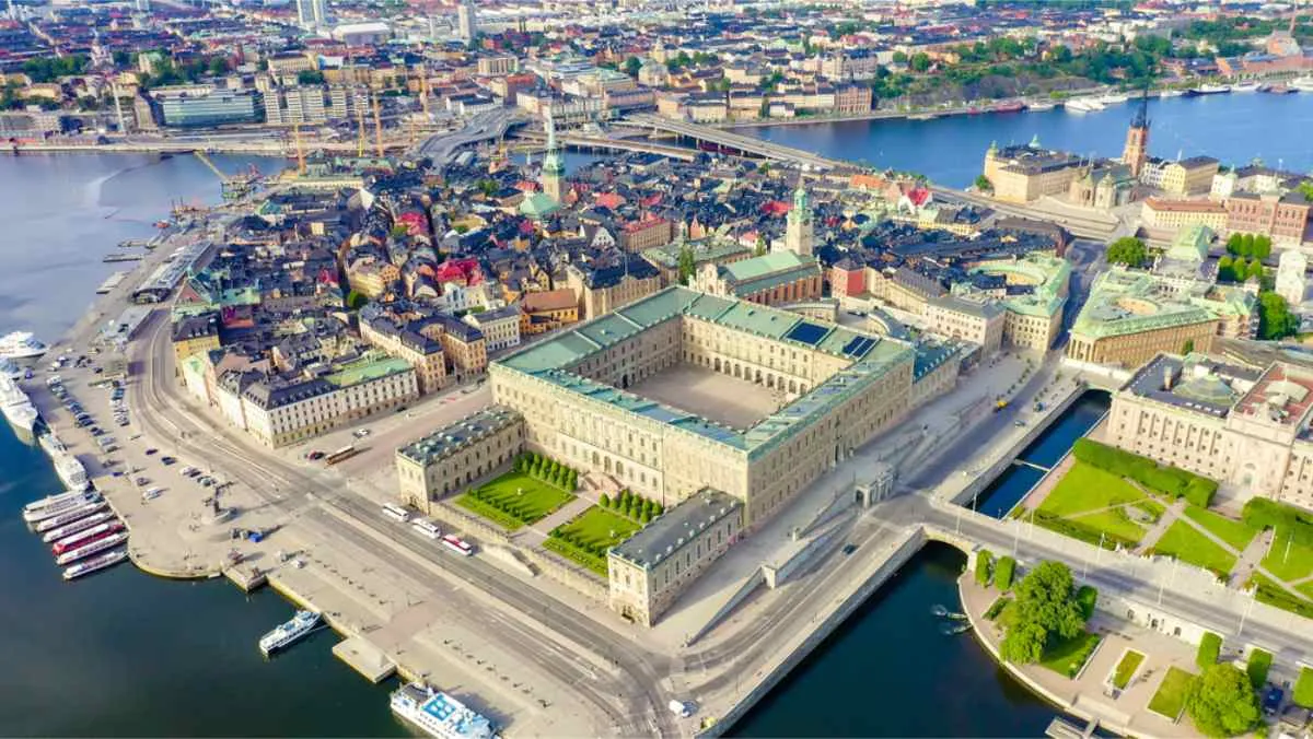 Drönarvy över Kungliga slottet i Stockholm under en vacker solig dag med Stockholms silhuett i bakgrunden.