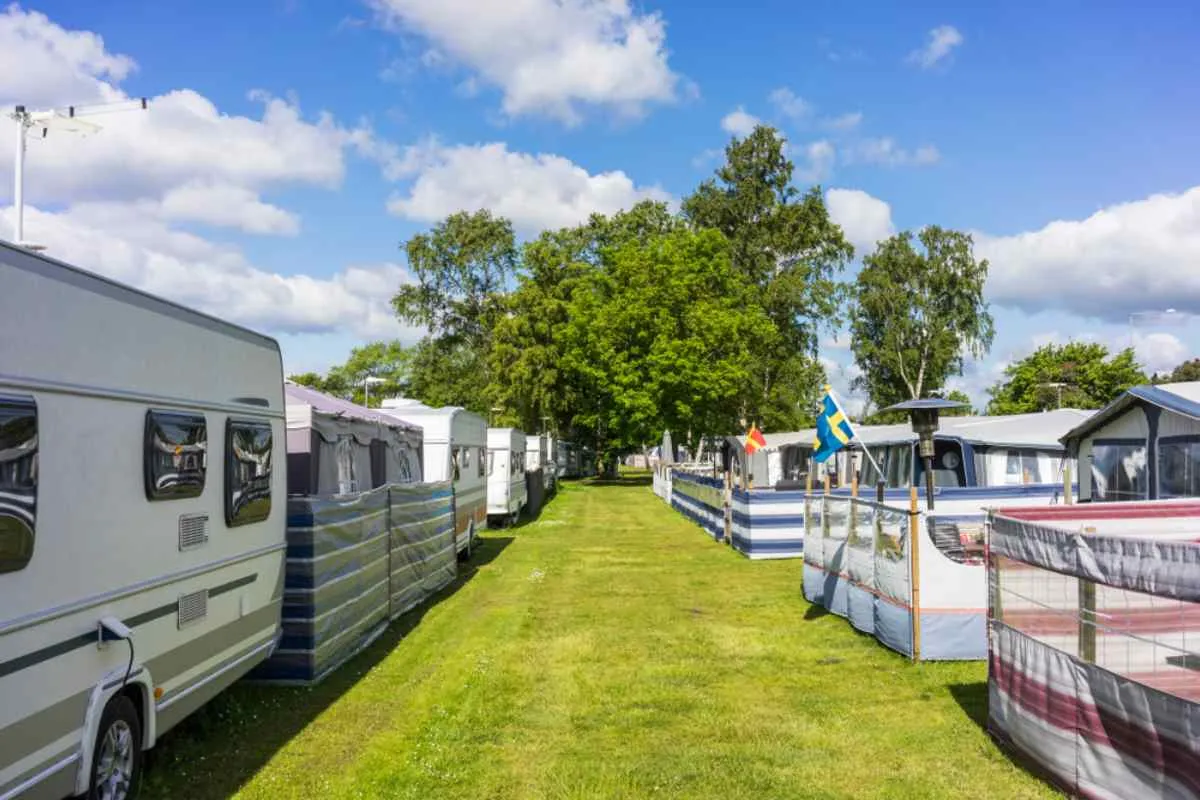 Una fila de autocaravanas y toldos en un camping ideal para familias en Suecia, en un soleado día de verano.