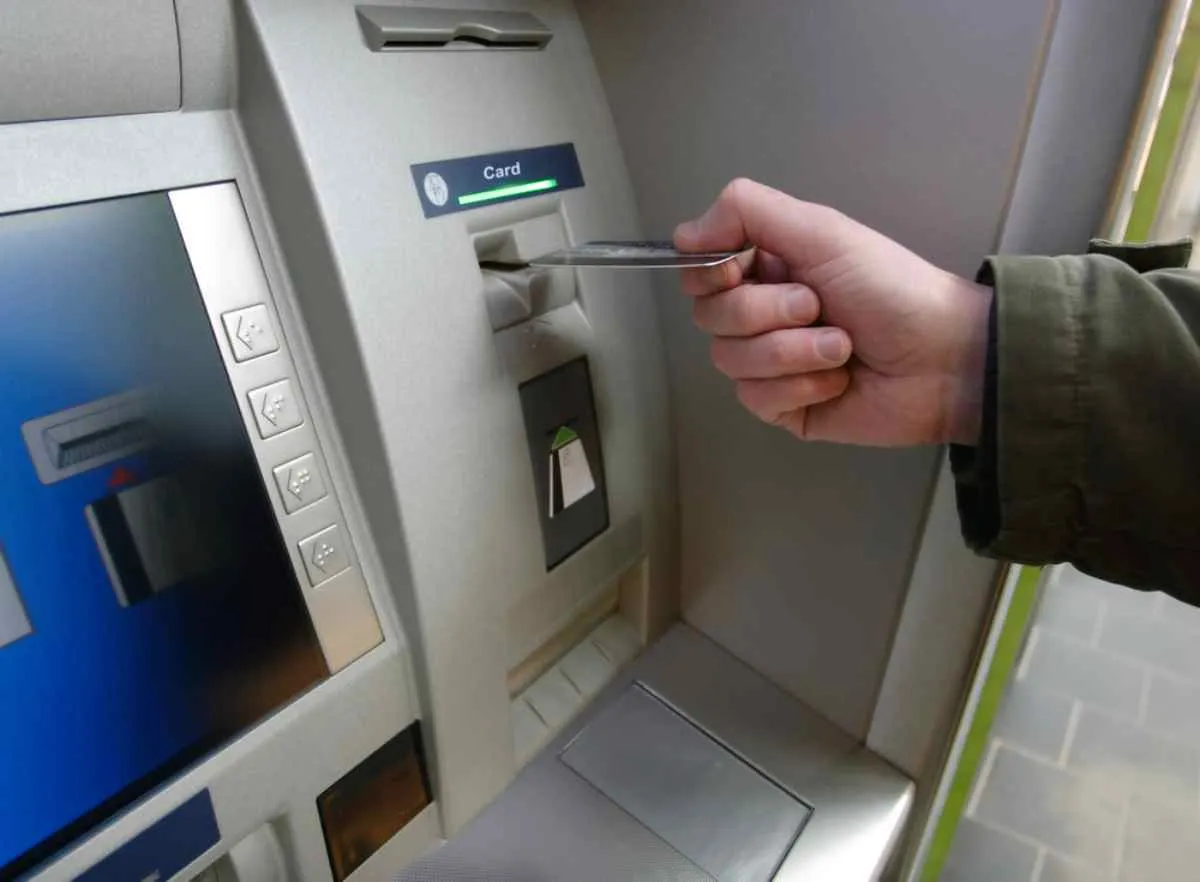 Une personne fait semblant de déposer une carte bancaire dans un distributeur automatique.