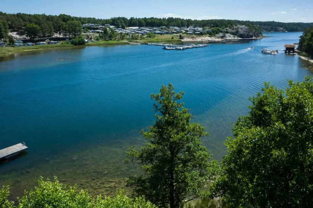 Vue d'ensemble d'un lac aux eaux turquoise et calmes, avec une forte activité humaine de l'autre côté du lac.