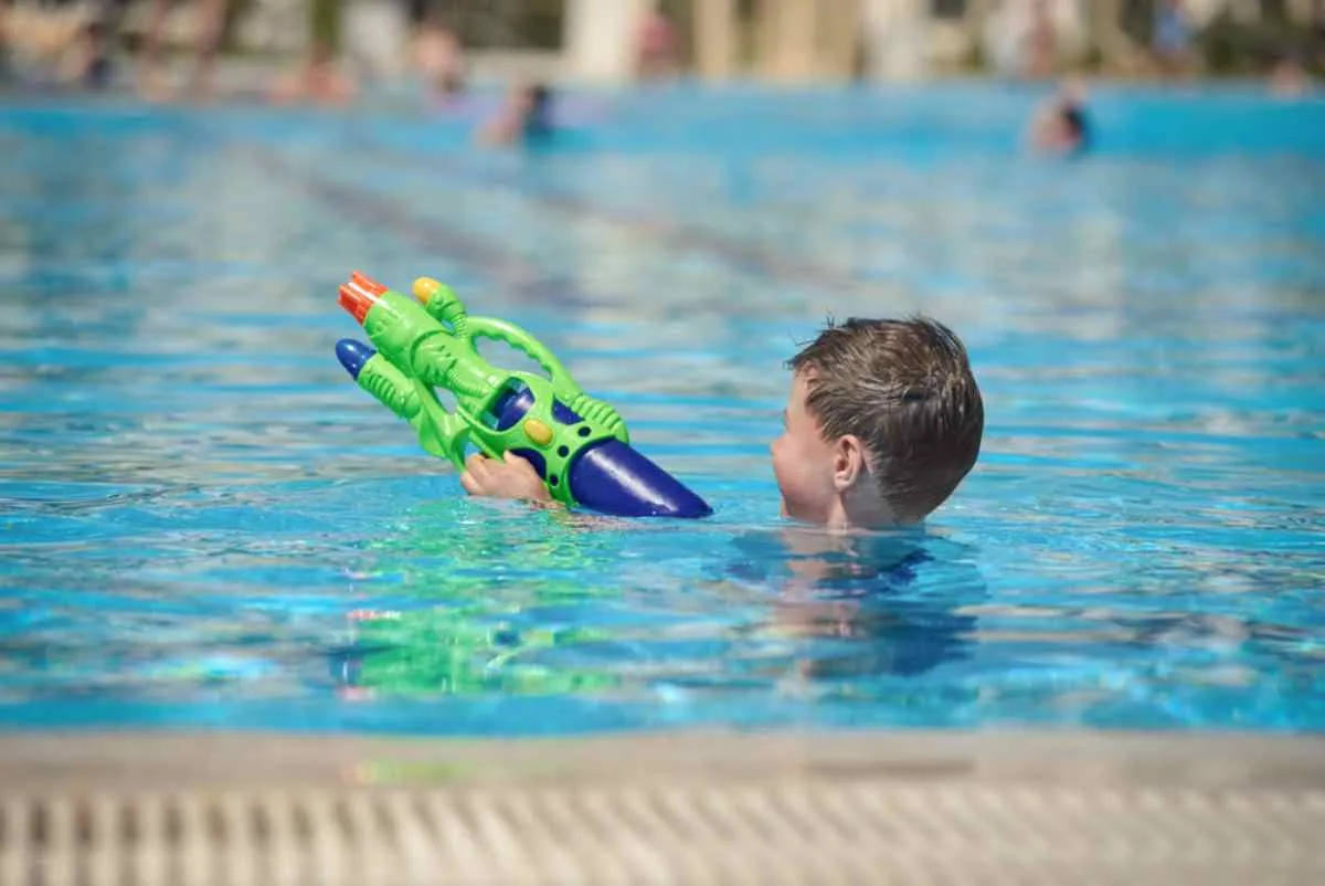 Un garçon s'amuse dans une piscine avec un pistolet à eau