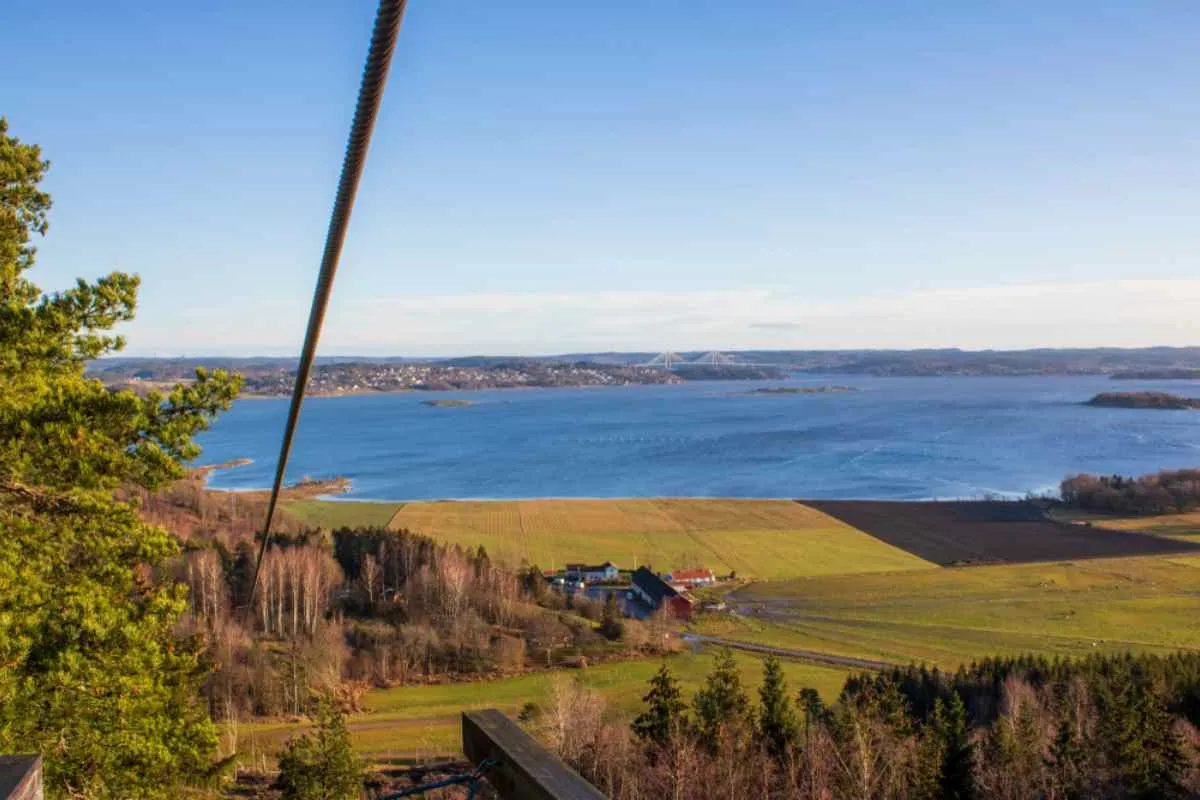 Vue d'ensemble d'une vallée près d'un grand plan d'eau bleue en Suède, avec une vaste esplanade verdoyante et aucune activité humaine visible de ce côté-ci de la rive.