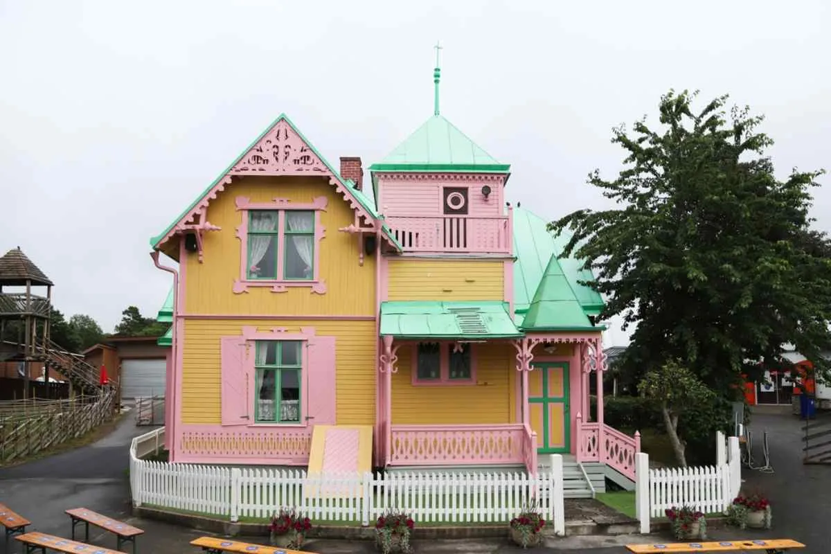 Vue d'ensemble de la façade de la maison originale de Fifi Brindacier, la Villa Villekulla, avec ses couleurs caractéristiques, le rose et l'orange.
