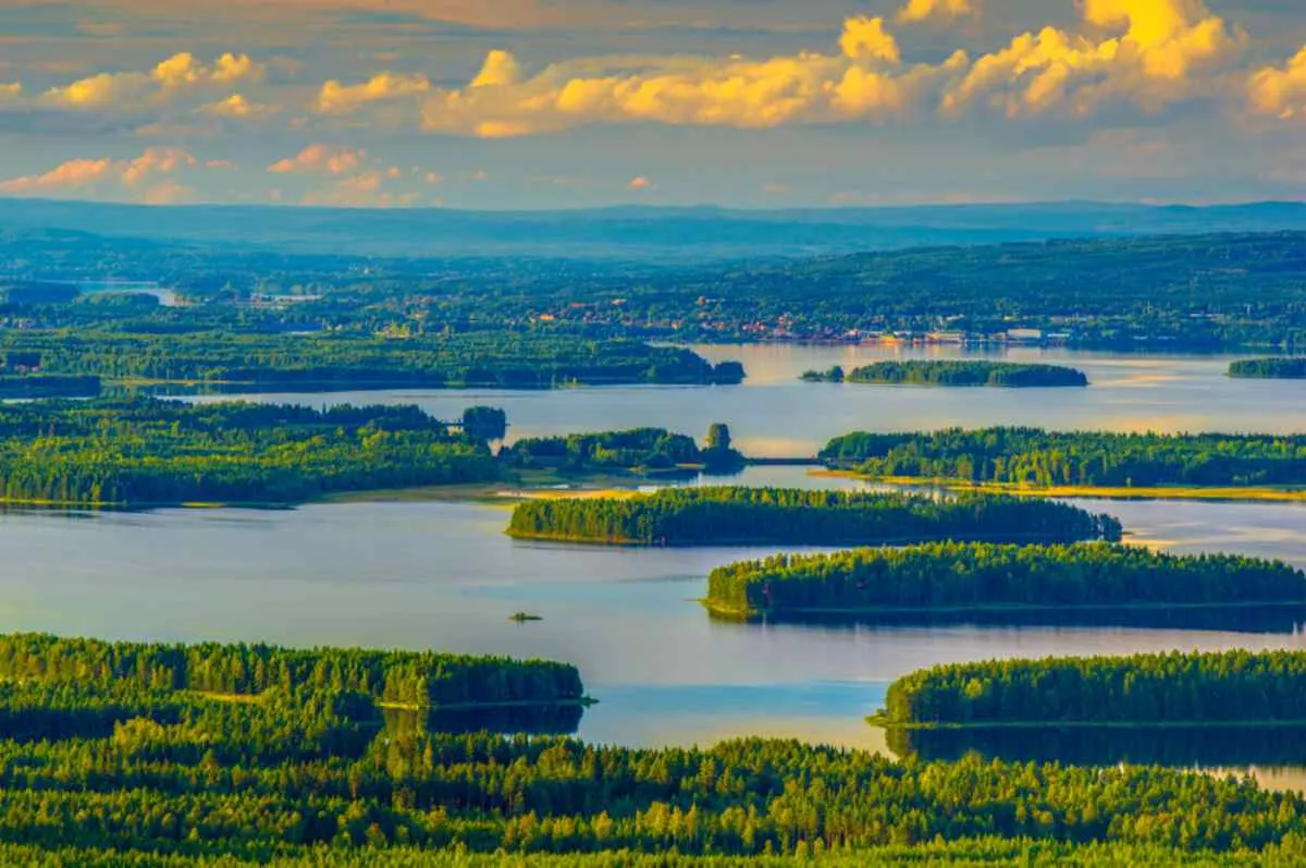 Vue aérienne prise par drone du lac Siljan, en Suède, au coucher du soleil, alors que les dernières lueurs du jour illuminent les nombreuses îles recouvertes de végétation verdoyante qui le parsèment.