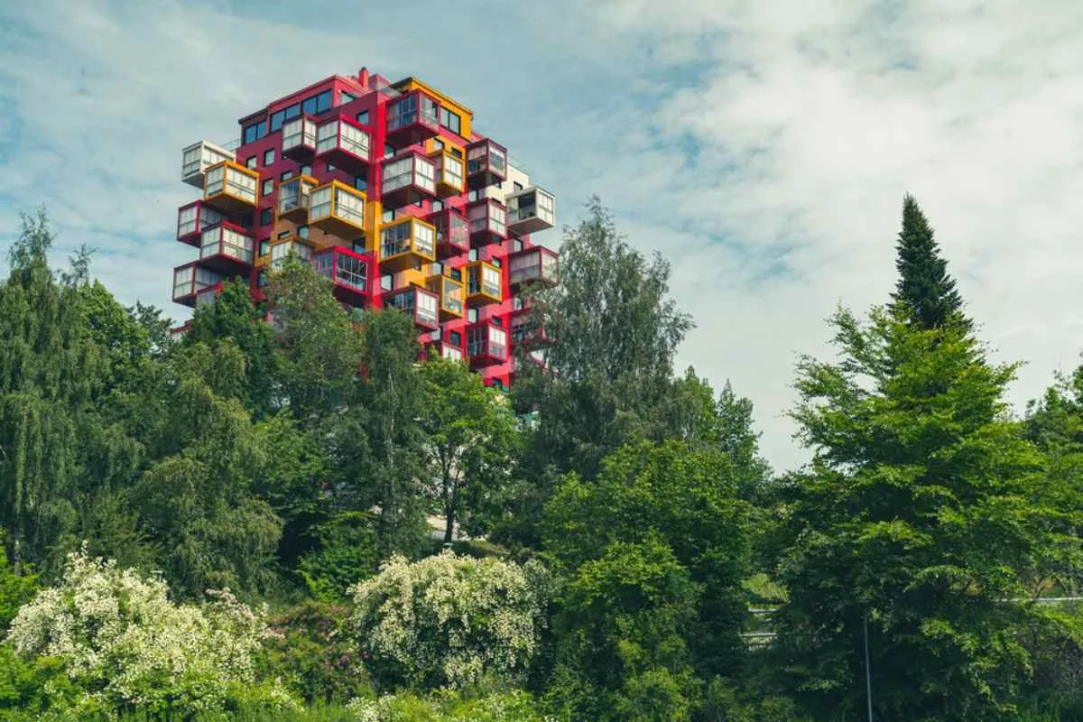 Un colorido bloque de pisos de estilo cúbico que se eleva por encima de frondosos árboles en Örnsköldsvik, un hito moderno en la Costa Alta de Suecia.