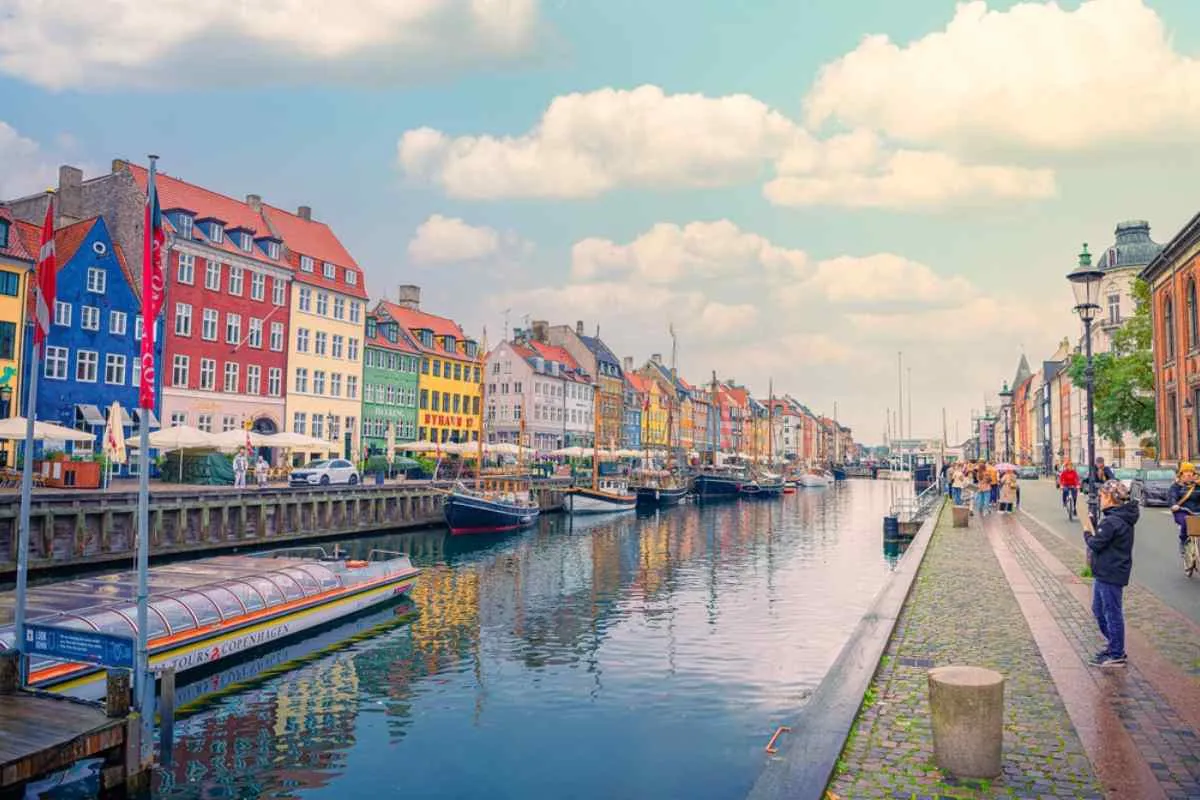 Edificios coloridos y barcos históricos alineados a lo largo del canal de Nyhavn, en Copenhague, en un día soleado.