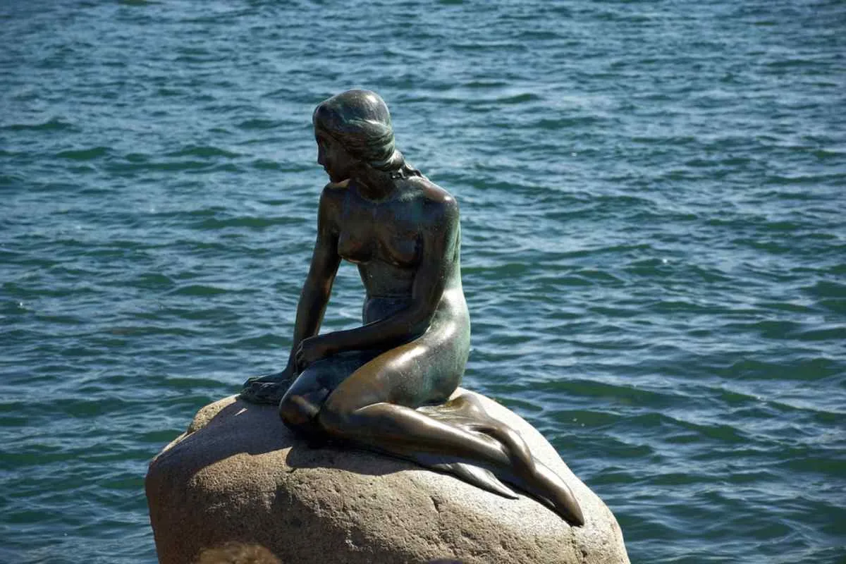 La estatua de La Sirenita sentada sobre una roca junto al mar en Copenhague, Dinamarca.