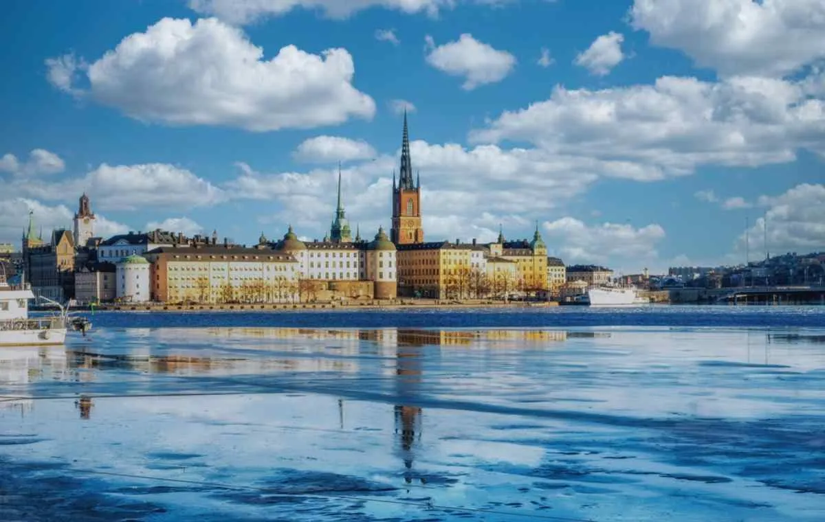 Vista de Gamla Stan, en Estocolmo, con edificios históricos reflejados en el agua parcialmente helada.