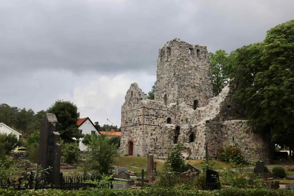 Ruines d'un château en pierre à Sigtuna, entourées de verdure sous un ciel nuageux.