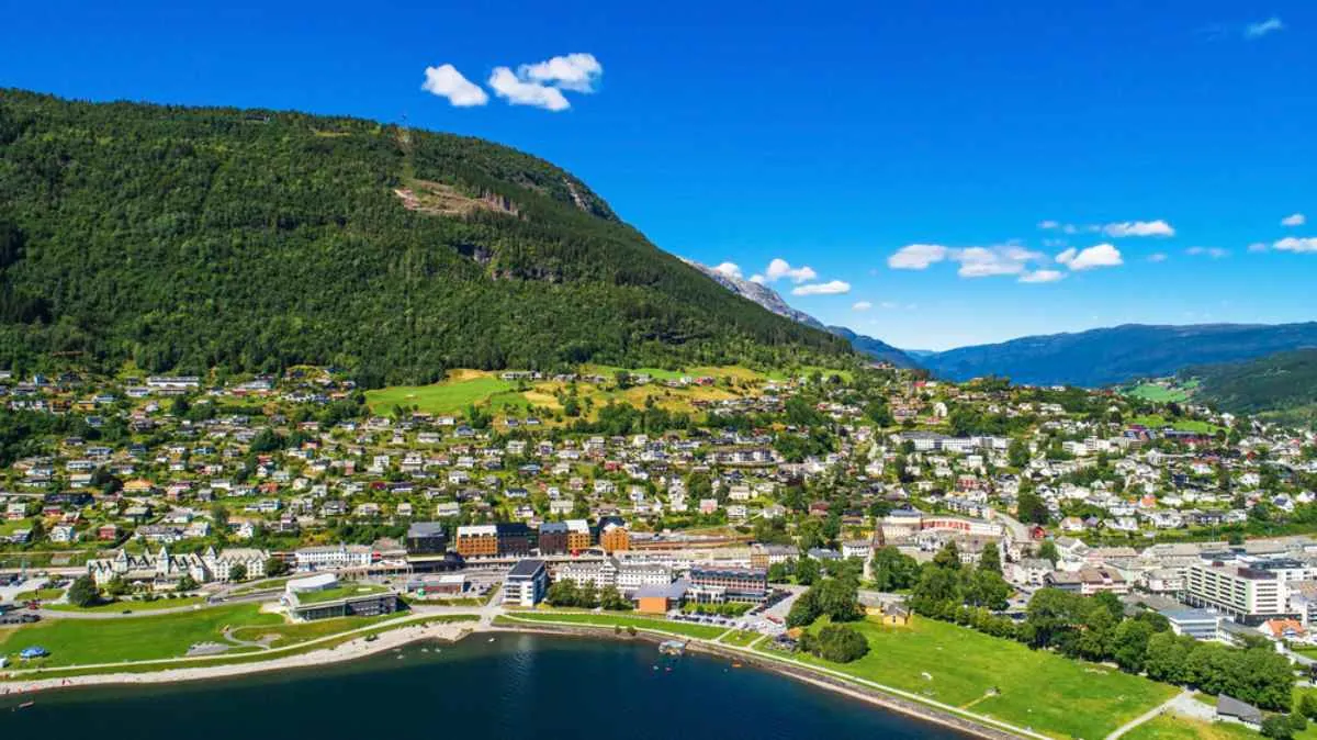 Vue aérienne de la ville de Voss, en Norvège, entourée de collines verdoyantes et d’un rivage lacustre.