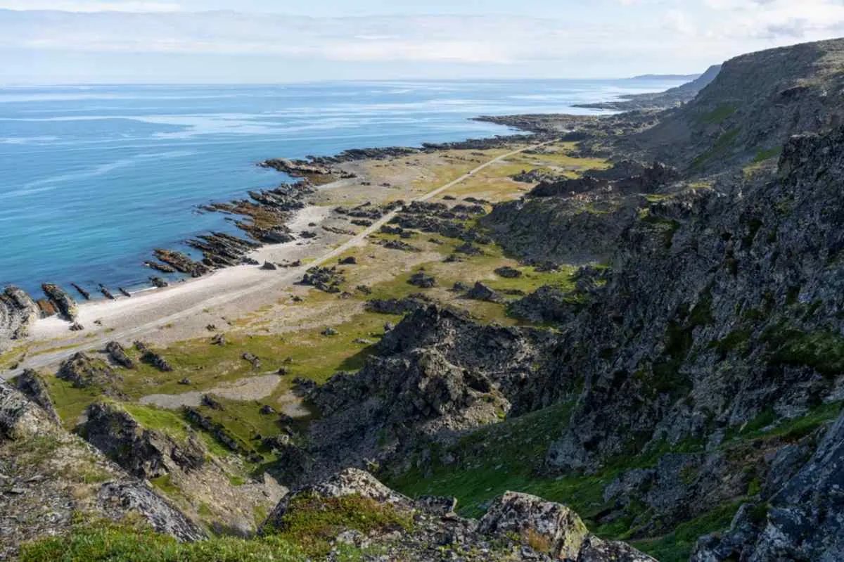 Una ripresa dal drone di una strada norvegese che attraversa quella che sembra una scogliera norvegese, circondata da grandi montagne.