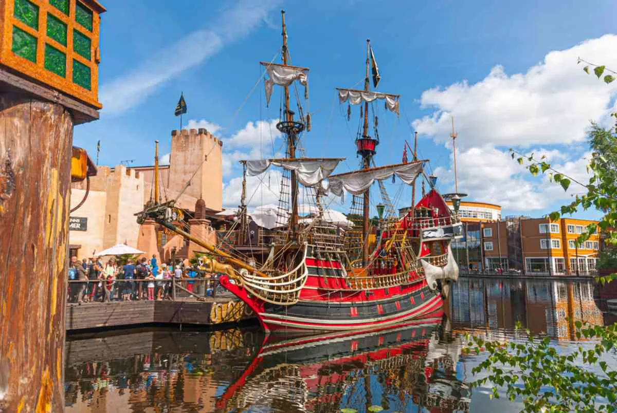 Färgglad attraktion i form av ett skepp i piratstil vid en norsk hamn, där familjer står i kö.