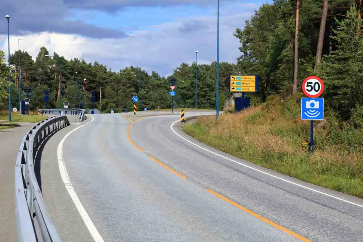 Norsk vei med et fartsgrenseskilt på 50 km/t og advarsel om fotoboks nær en rundkjøring.