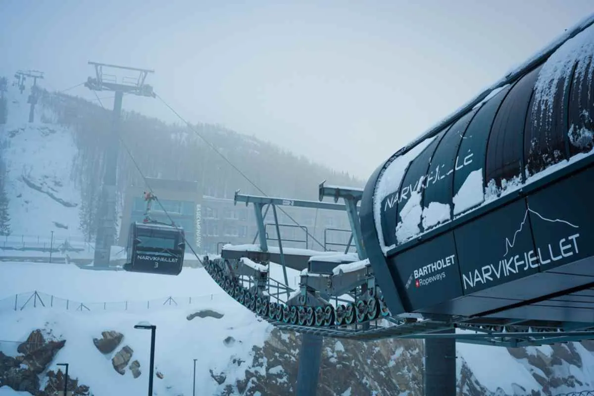 Stazione degli impianti di risalita a Narvikfjellet circondata dalla neve, con una cabinovia che si avvicina in una giornata invernale nebbiosa
