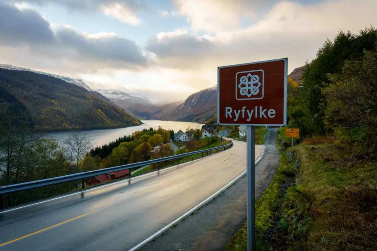 Panoramica di una strada norvegese vicino a Ryfylke, con un cartello che annuncia l’arrivo in questa zona del paese e una spettacolare valle con i fiordi dall’altra parte.
