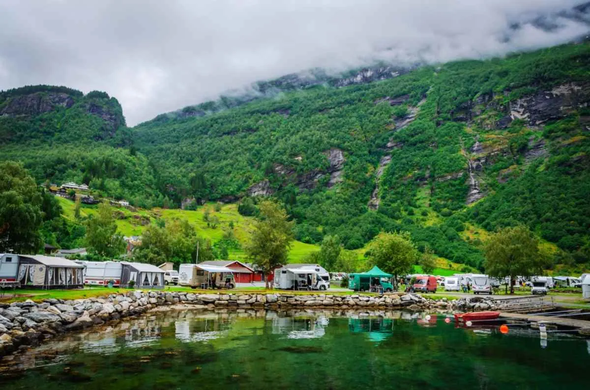 Campingplats vid vattnet med husbilar och stugor intill en fjord längs den norska E39.