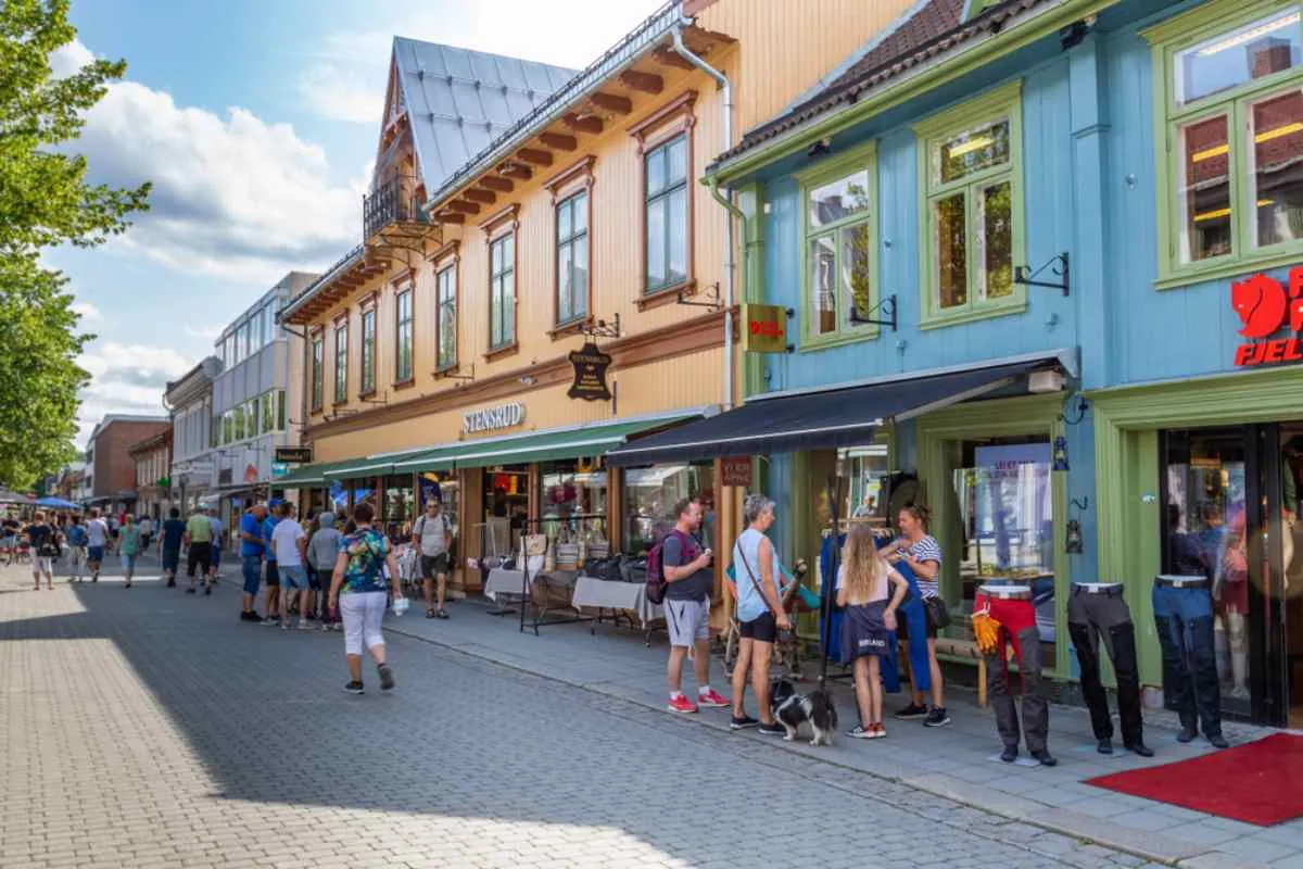Gågata i Lillehammer, Norge, med färgglada trähus och människor som promenerar.