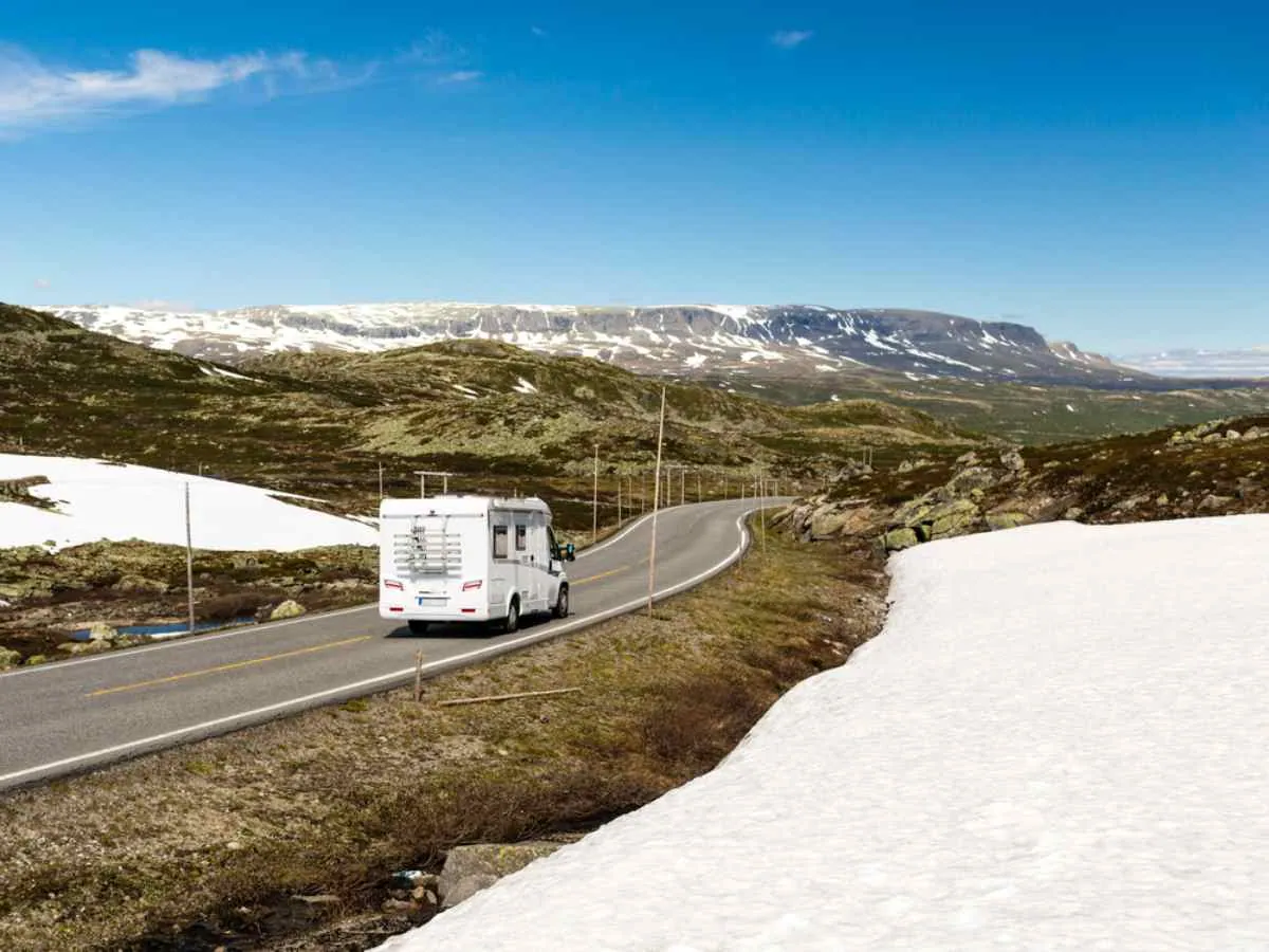 Bobilkjøring på fjellveien RV7 i Norge med snøflekker og vidstrakt utsikt over platået.