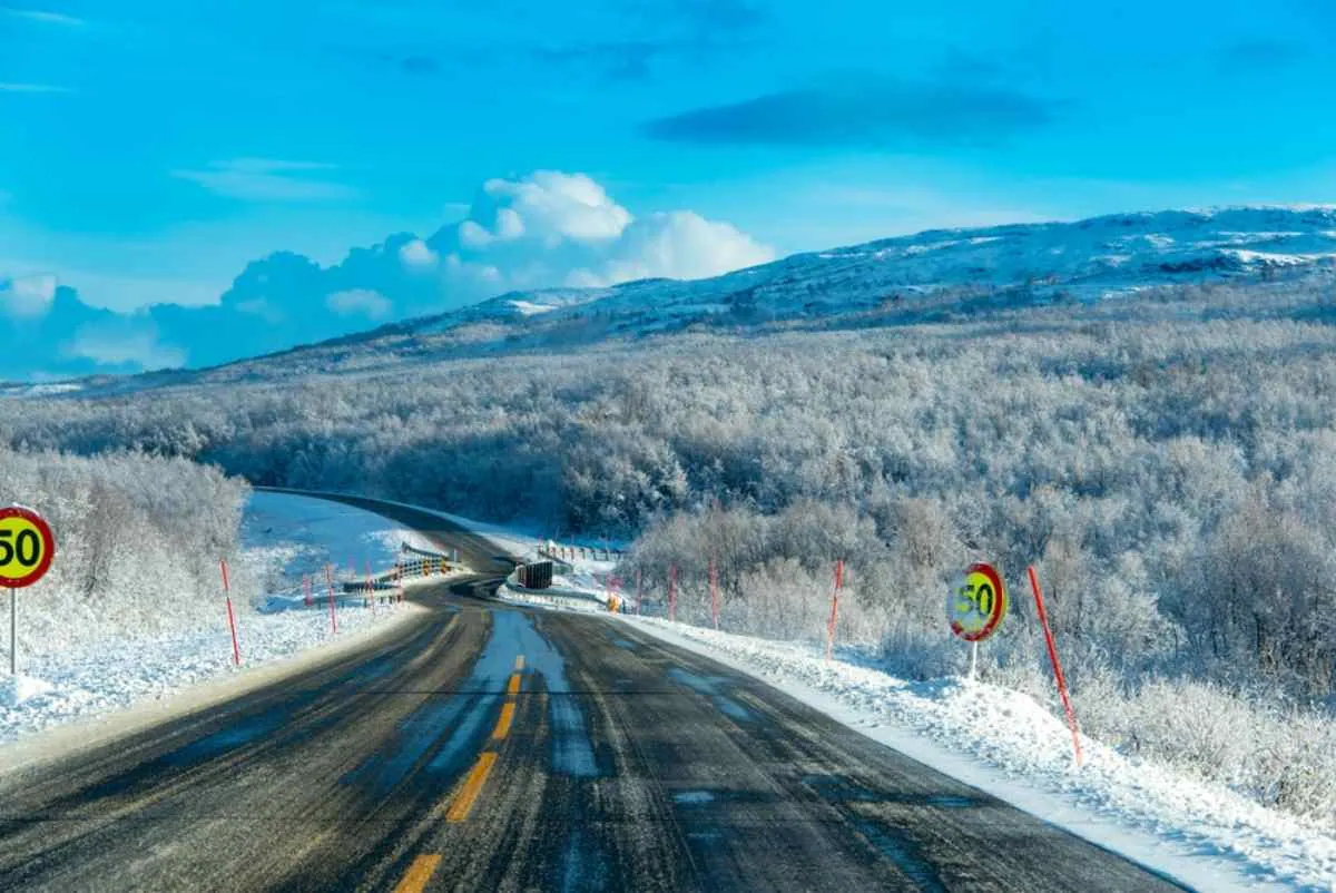 Vinterväg på E6 i Norge med hastighetsbegränsningsskyltar på 50 km/h och ett snötäckt skogslandskap.