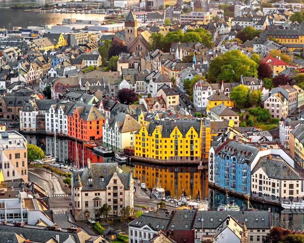 Farbenfrohe Stadt am Wasser mit Kanal, Booten und pastellfarbenen Gebäuden, die sich im warmen Licht um eine Kirche gruppieren.