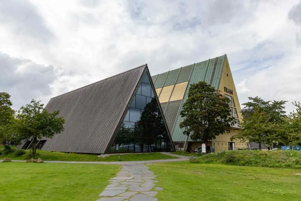Ein kantiges, modernes Museumsgebäude mit begrüntem Dach und einem „FRAM“-Schild neben einem grasbewachsenen Weg unter bewölktem Himmel