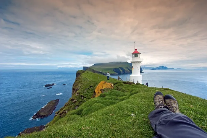 Un touriste en train de se reposer sur une pelouse verte lors de son voyage aux Îles Féroé