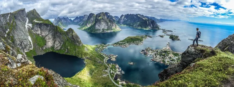 Panoramautsikt over Lofoten med en turist på kanten av en klippe – Topp 10 turistdestinasjoner i Norge