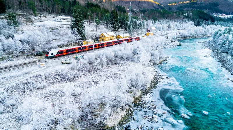 Train Oslo-Bergen au milieu des montagnes enneigées, le long de la rivière - Tout sur Bergen, en Norvège
