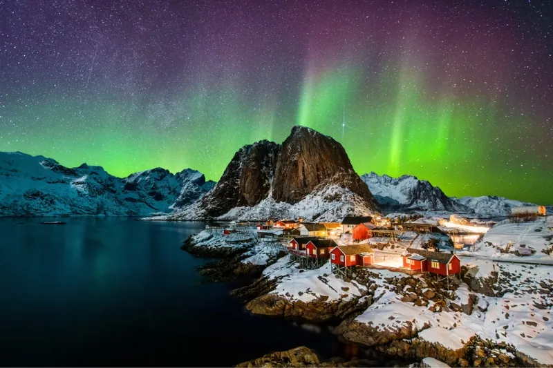 Et nordlys i Norge, med en kystby i forgrunnen